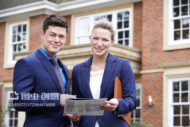 站在住宅物業(yè)外面的男女房地產(chǎn)經(jīng)紀(jì)人Male And Female Realtor Standing Outside Residential Property